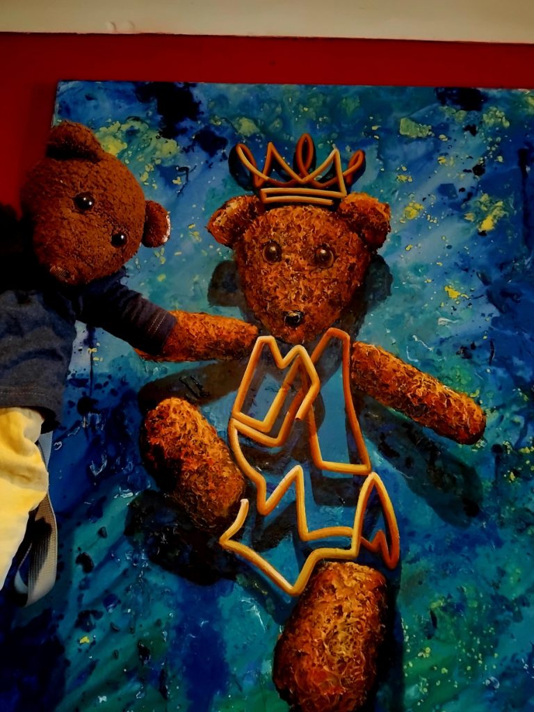 Paint portrait of Bearsac the teddy bear with Bearsac besdie it.
