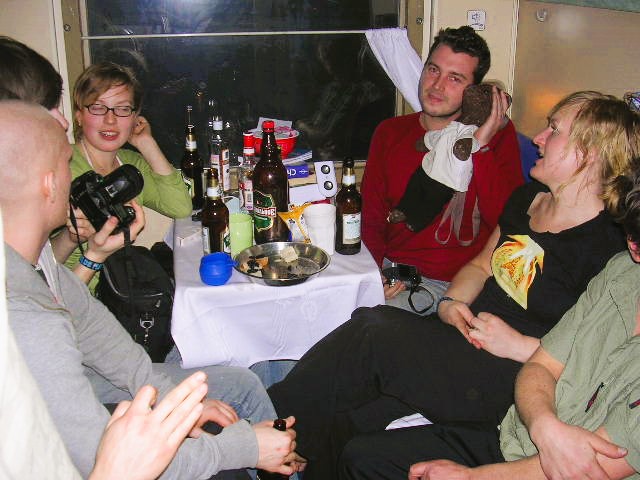Bearsac being held by a man during a party on the train with other passsengers