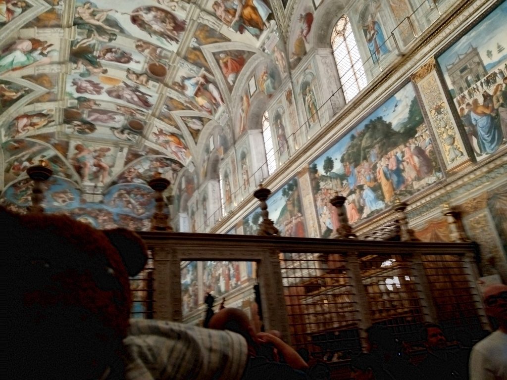 Bearsac the teddy bear in forground of the Sistien Chaple ceiling